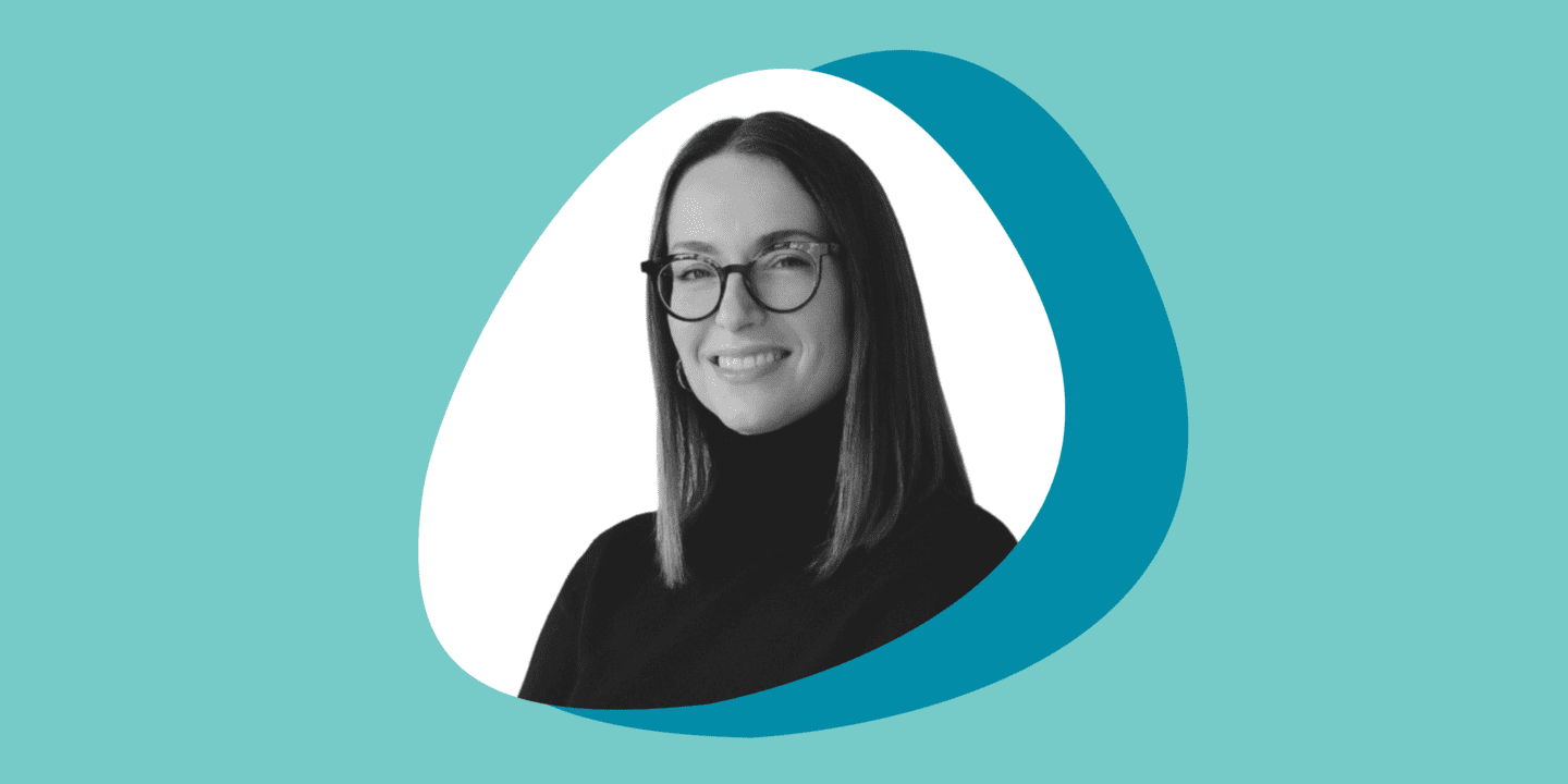 Black and white portrait photo of a woman in glasses smiling at the camera in a circular frame, set against overlapping teal and turquoise circles on a light teal background