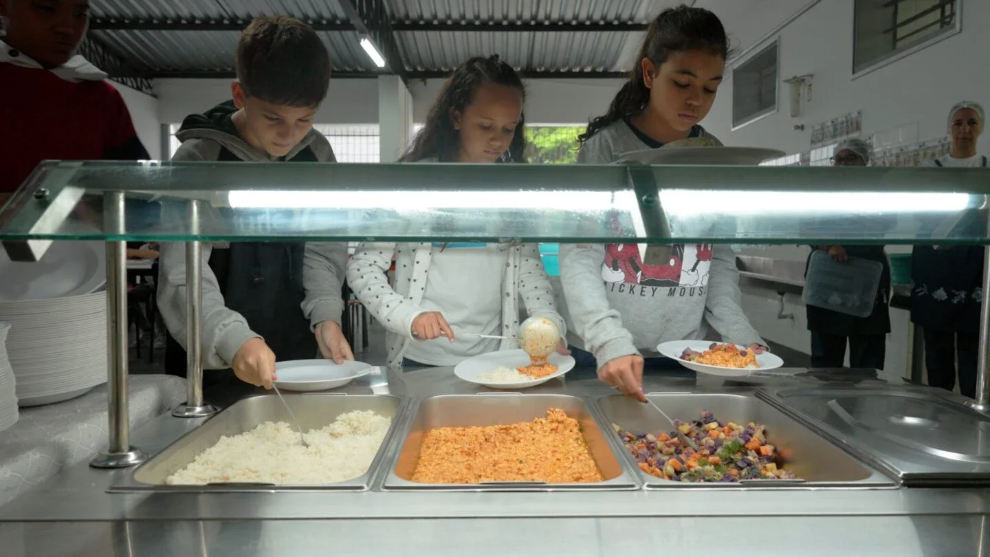 students serve themselves food at a school cafeteria buffet line